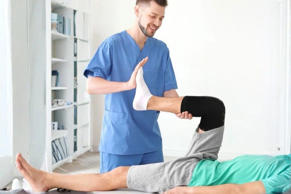 Therapist assisting patient using knee ice pack sleeve in medical and rehabilitation recovery