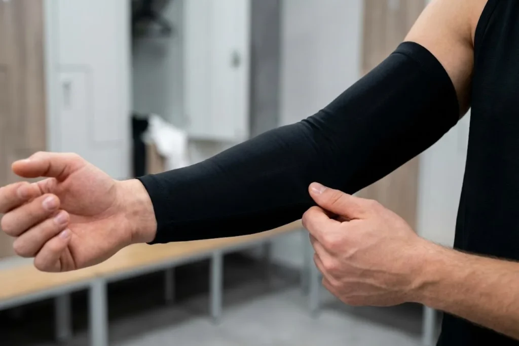 Athlete carefully smoothing the fabric of a black arm sleeve to ensure a secure fit