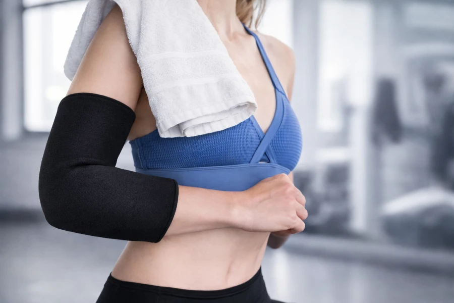 Athlete using compression arm sleeve and cold wrap for elbow recovery