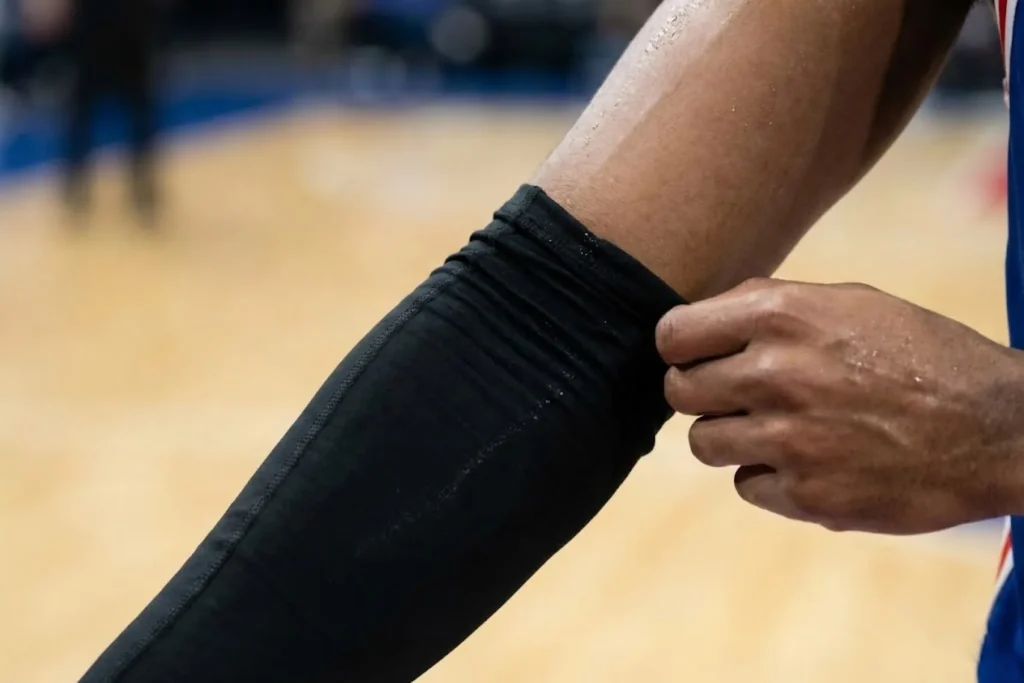 Basketball player adjusting a sweaty arm sleeve that has slid down during a game