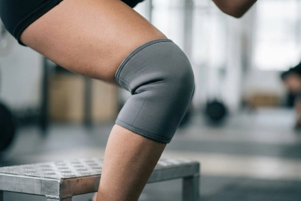 Correct snugly fitting grey compression knee pad on an athlete during controlled movement