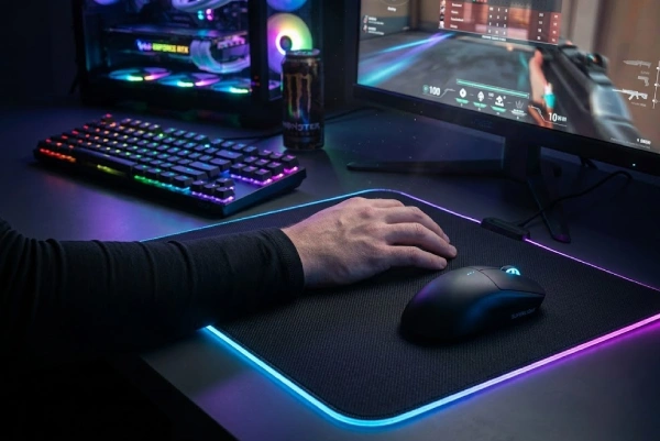 Gamer arm in a black sleeve on an RGB mousepad next to a mouse