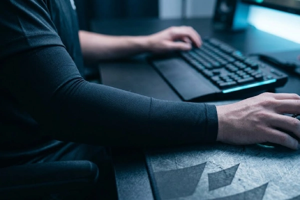 Gaming sleeve close-up worn by esports player with mousepad and keyboard