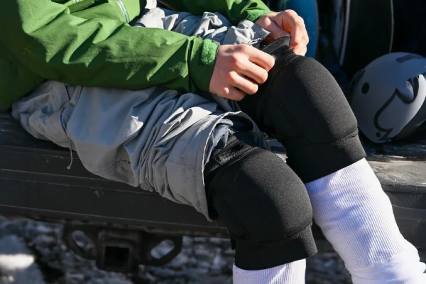 Knee pads are being worn and adjusted by a person sitting outdoors