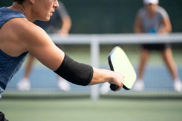 Pickleball elbow support _ compression sleeve worn by a player during a swing