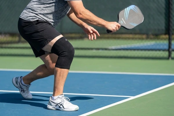 Pickleball player wearing a knee compression sleeve during a quick stop motion