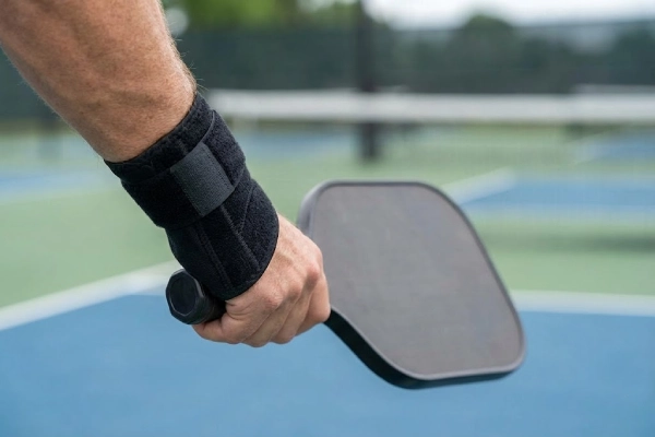 Pickleball wrist brace worn by a player gripping a paddle on the court