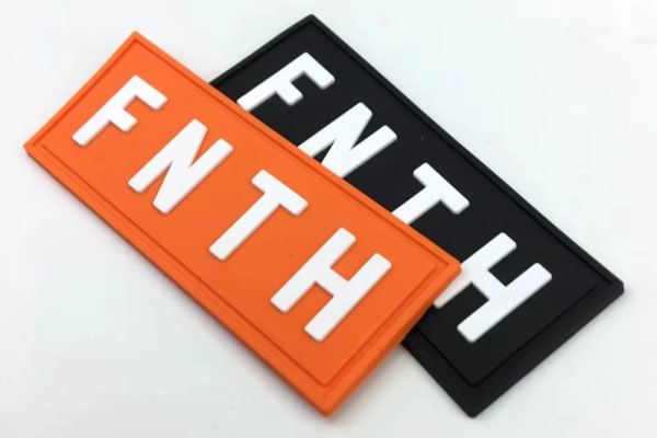 Two rectangular Silicone Patches in orange and black showing embossed logo branding options