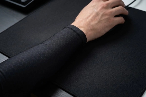 Tight-fitting gaming arm sleeve providing a smooth, wrinkle-free surface on a cloth mousepad