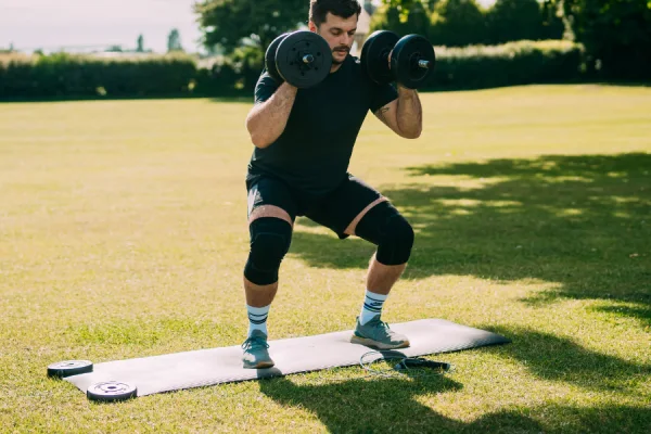 Man performing outdoor squats with knee sleeves for weightlifting in varied training scenarios